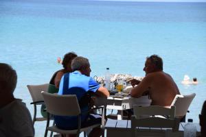 a group of people sitting at a table by the ocean at Fiore Beach Studios in Vasilikos
