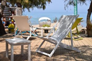 two lawn chairs and a table on the beach at Fiore Beach Studios in Vasilikos