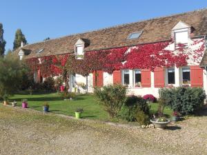 dom z czerwonym bluszczem na boku w obiekcie Ferme les Rousseaux w mieście La Belliole