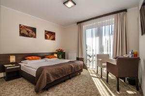 1 dormitorio con cama, escritorio y ventana en Hotel Emocja SPA en Mielno