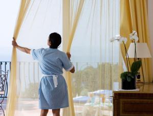 Kobieta w niebieskiej sukience patrzy przez okno w obiekcie Casa Morgano w mieście Capri