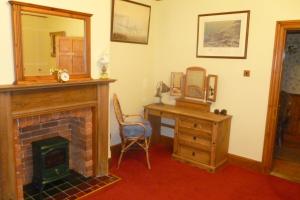 um quarto com uma lareira, uma secretária e um espelho em The Ramblers Retreat em Abergele