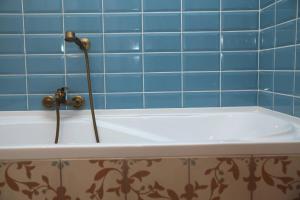 a bath tub in a bathroom with blue tiles at Rozmaring Pihenőház in Velence +5 photos