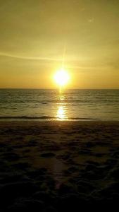 a sunset on a beach with the ocean at Chill land house in Bang Tao Beach