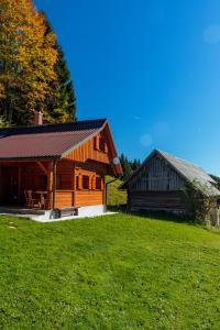 een blokhut en een schuur op een grasheuvel bij Holiday house Pokrovec - Bohinj in Bohinj