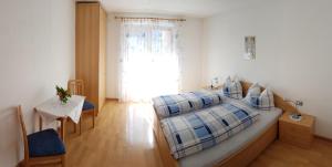 - une chambre avec un lit, une table et une fenêtre dans l'établissement Appartements Oberleiter, à Valdaora