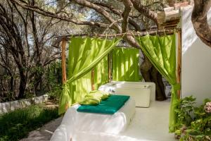 um quarto com uma cortina verde e uma cama com almofadas em Su Gologone em Oliena
