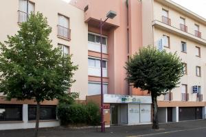 apartamentowiec z drzewami przed nim w obiekcie Brit Hotel Cahors - Le Valentré w mieście Cahors