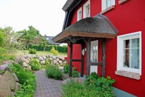 ein rotes Haus mit einem Fenster und einem Backsteinsteg in der Unterkunft Karolas Landhus unterm Reetdach in Neu Reddevitz