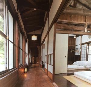 南木曾町的住宿－Takimi Onsen Inn that only accepts one group per day，带两张床的客房和窗户的走廊