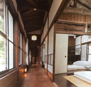 a room with two beds and a hallway with windows at Takimi Onsen Inn that only accepts one group per day in Nagiso