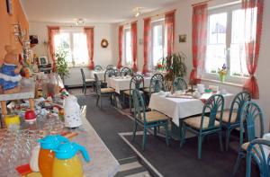 a dining room with tables and chairs and windows at Selliner Pension am Waldrand in Ostseebad Sellin