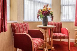 a room with two chairs and a table with a vase of flowers at The Montana Hotel in London