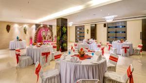 un salón de banquetes con mesas y sillas blancas en Sonotel Hotels & Resorts Pvt Ltd, en Dhanbād