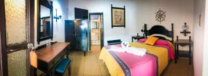 a bedroom with a bed and a table and a desk at Hotel Villa de Flores in Uruapan del Progreso