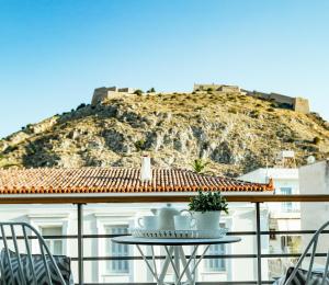een tafel op een balkon met een berg op de achtergrond bij Filoxenion Luxury Rooms & Lofts in Nafplio