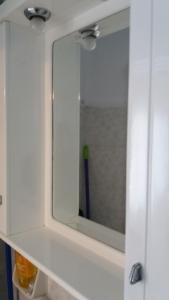 un espejo en un armario blanco con cepillo de dientes en Anthi's Cottage, en Kastellánoi