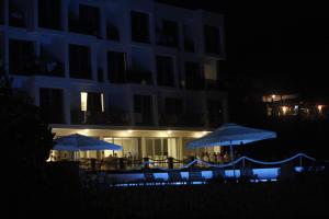 a group of tables with umbrellas in front of a building at night at Bara Bay in Metajna