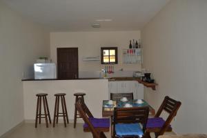 a kitchen with a bar with stools and a table at Chale Buzios Praia Rasa in Búzios