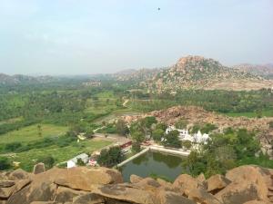 a large pool of water with mountains in the background at Mayuram Homestay in Hampi