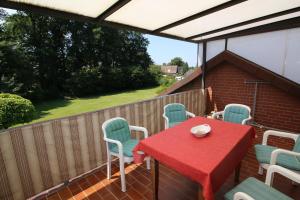 a patio with a red table and chairs and a fence at FEWO am Dümmer-See in Lembruch