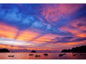a group of boats on the water at sunset at Pangkor Holiday Home in Pangkor