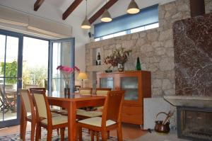 ein Esszimmer mit einem Tisch, Stühlen und einer Steinmauer in der Unterkunft HOMEinLAND of TERROSO - Privat Pool, Grill & Seaview in Póvoa de Varzim