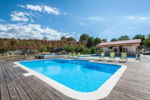 a swimming pool on a deck with chairs and a house at Holiday Home Poljičko Imanje in Donji Dolac