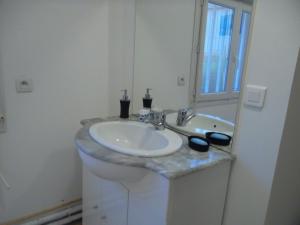 W białej łazience znajduje się umywalka i lustro. w obiekcie Les Chambres Du Rochereuil w mieście Bédée