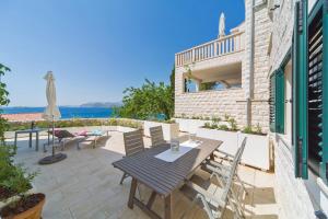 un patio con mesa, sillas y el océano en I Sassi Bianchi - East Villa, en Cavtat