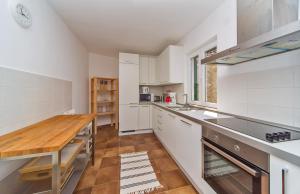 a kitchen with white cabinets and a wooden table at I Sassi Bianchi - East Villa in Cavtat