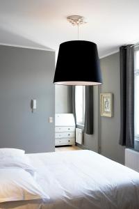 a bedroom with a white bed and a black lamp at Le Vaudeville in Brussels