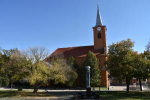 a church with a tall steeple with a clock tower at Malomszeg Apartman in Pécs