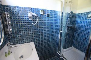 a blue tiled bathroom with a shower and a sink at Mas de L'Ermitage in Lattes