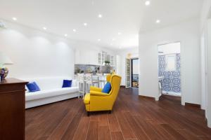 a living room with a yellow chair and a kitchen at Casa del Saraceno in Massa Lubrense
