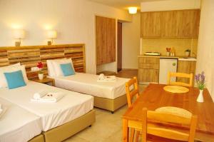 a room with two beds and a table and a kitchen at Cleopatra Apartments in Hersonissos