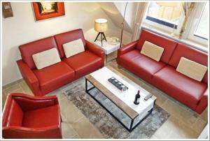 Sala de estar con 2 sofás rojos y mesa de centro en FERIENWOHNUNG DEICHWIESE SYLT-WESTERLAND 2-5 Personen-3 Schlafzimmer-Terrasse, en Westerland