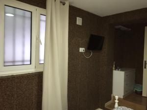 a bathroom with a curtain and a television on the wall at Jualis Guest House in Porto