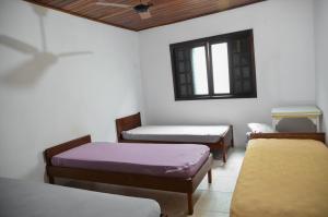 a room with three beds and a window at Condomínio Higa in Peruíbe