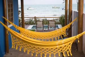 a yellow hammock sitting on a porch next to the beach at Pousada Ecohar Yoga in Maragogi