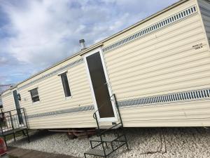 a large white trailer parked in a gravel lot at Taylor's Caravan Holiday's 8 Berth (Coral Beach) in Ingoldmells