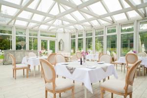 a dining room with white tables and chairs and windows at Dworek Bukowy Park in Szczecin