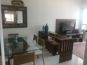 a dining room with a glass table and a television at UBATUBA, APARTAMENTO TOP in Ubatuba