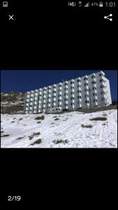 un gran edificio blanco en la nieve junto a un edificio en estudio muy acogedor, en Sierra Nevada 3 fotos más