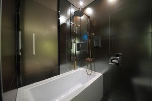 a bathroom with a tub and a glass shower at Cullinan Gaepo in Seoul
