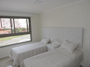 2 camas en una habitación blanca con ventana en IMPERIALE Luxury Apartment, en Punta del Este