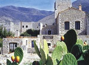 a large stone building with mountains in the background at Katafigi in Pirgos Dhirou