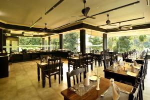 ein Esszimmer mit Tischen und Stühlen sowie ein Restaurant in der Unterkunft Casa Rio Resorts Athirappilly in Athirappilly