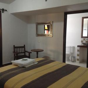 a bedroom with a bed and a table and a mirror at Posada Aguila Real in Palenque