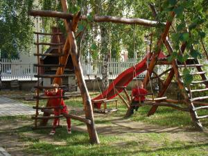 two children in red uniforms playing in a playground at Lázár Pension & Restaurant in Gheorgheni